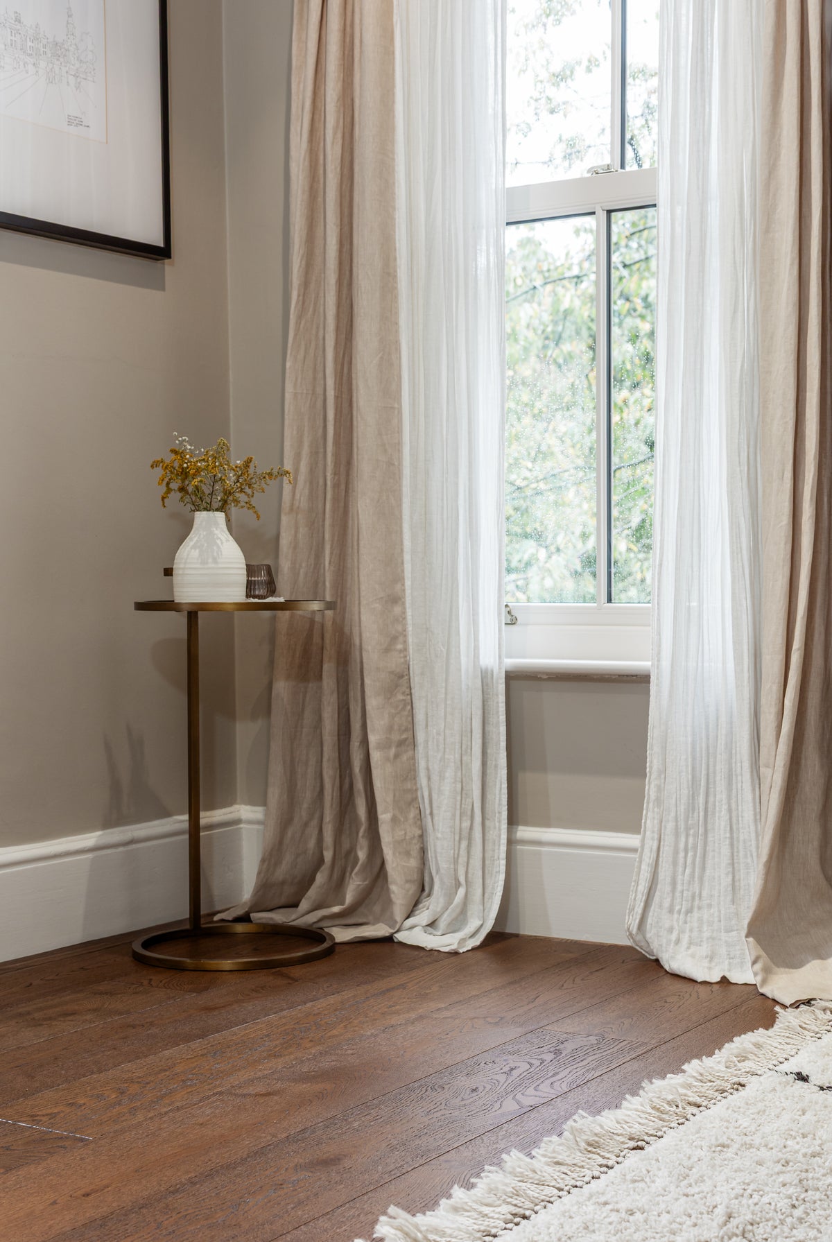 Dark oak planks in the corner of a room with draping curtains and a side table